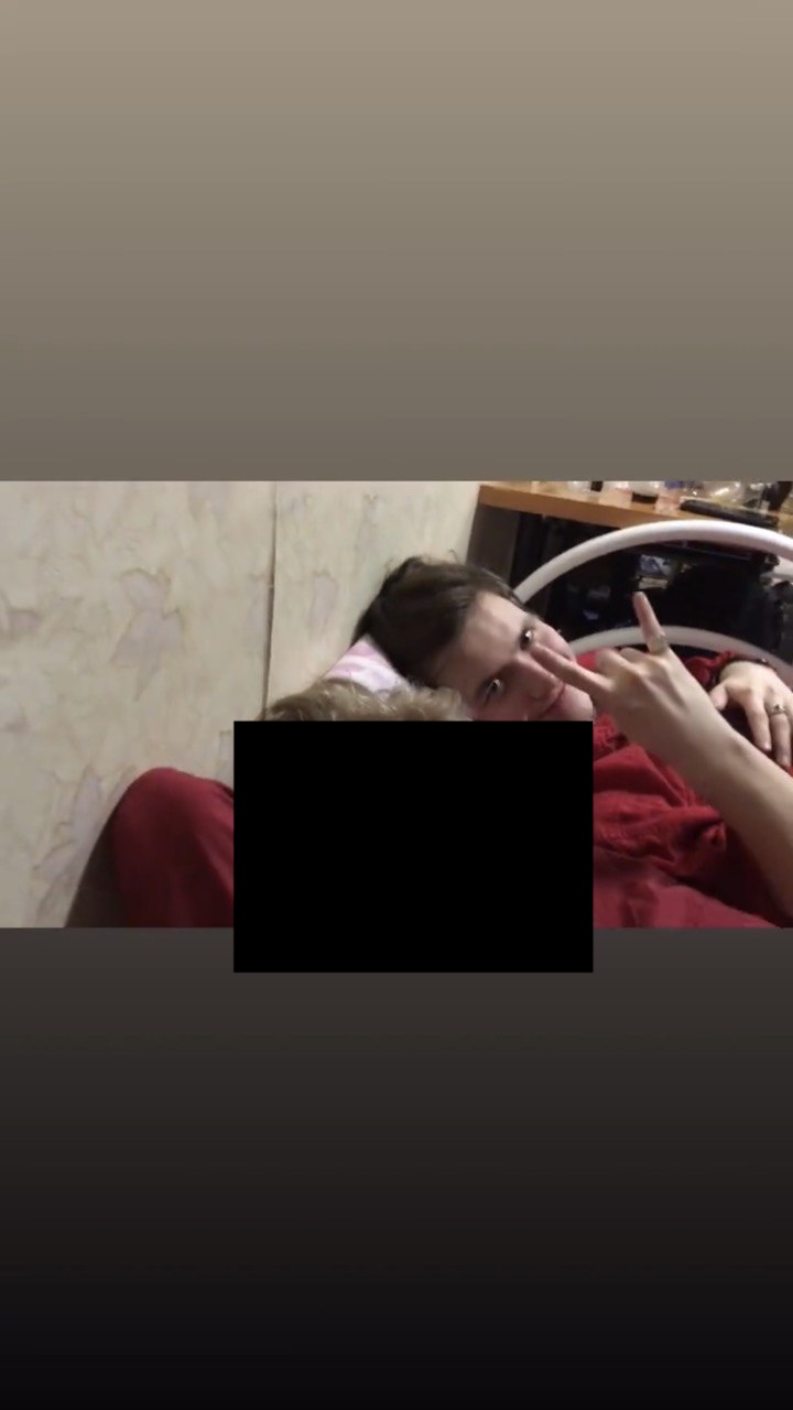 Двое лежат рядом, один показывает знак пальцами в камеру, часть кадра закрыта чёрным