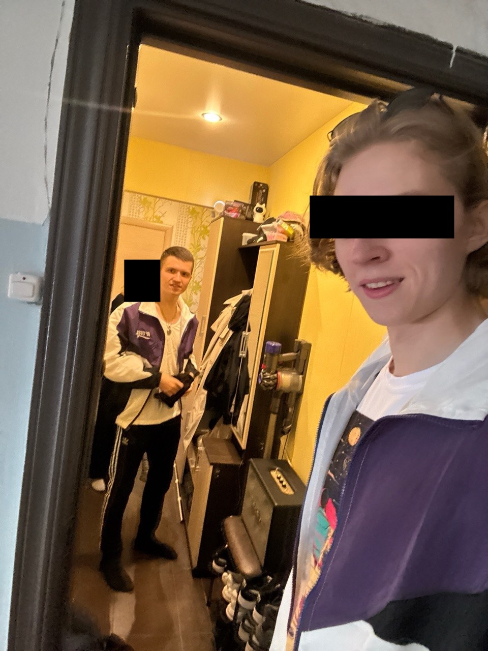 Селфи в дверном проёме, в глубине коридора стоит ещё один человек; лица закрыты чёрными прямоугольниками